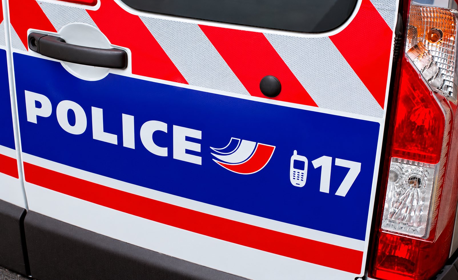 Gros plan sur la porte arrière d'un fourgon de police français bleu, blanc et rouge portant l'inscription POLICE et le numéro 17.